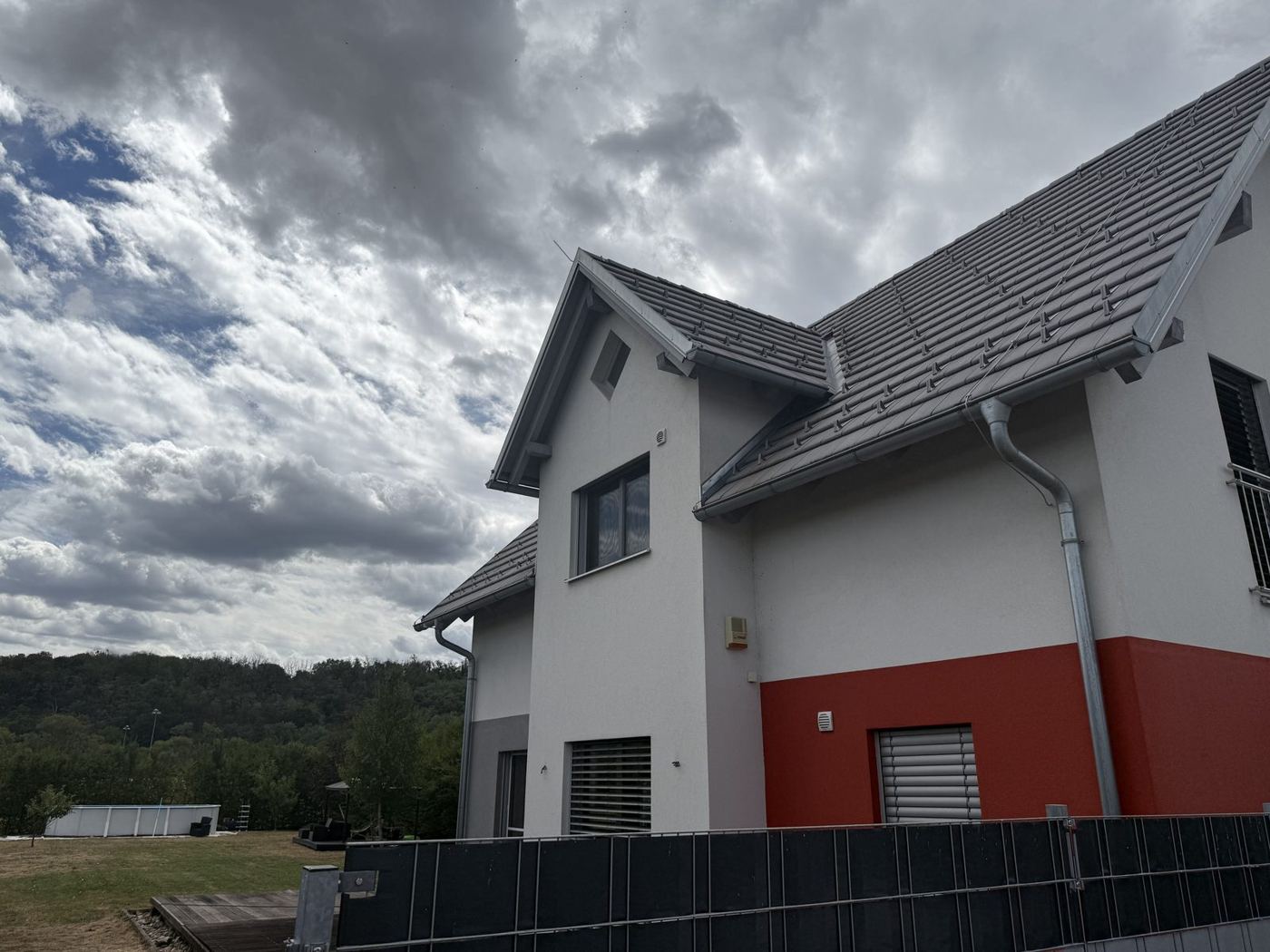 Freistehendes Einfamilienhaus mit roter und weißer Fassade, Satteldach, davor Garten